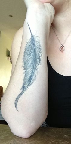 a woman with a feather tattoo on her arm