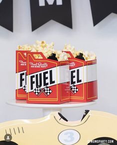 two cans of fuel el sitting on top of a cake plate with black and white bunting