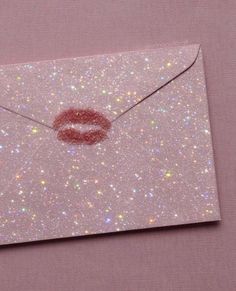 a glitter envelope with a lipstick kiss on the front and bottom flap open to reveal a pink background