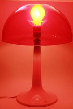 a red table lamp with a yellow light on it