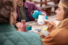 three people sitting at a table with coffee cups and mugs in front of them