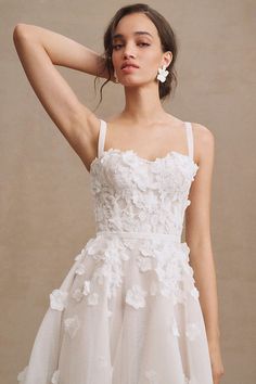 a woman wearing a white dress with flowers on it and her hair in the air