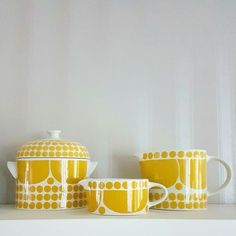 three yellow and white dishes sitting on top of a shelf next to each other in front of a wall