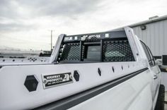 the back end of a white truck parked in front of a metal structure and building