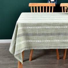 a table with two chairs and a green wall in the background, next to a wooden chair