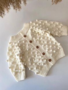 This adorable Popcorn baby cardigan is knitted from soft yarn. The sweater has hand knitted popcorn scattered all over, front and back. This style is so gorgeous.  You can order this handknit set as a gift for baby shower gift, christening gift, Pregnancy gift, Granddaughter gift, Grandchild gift, Christmas gift or special occassion.  There is a front closure with coco buttons. Moreover, the cardigan is knitted with a raglan fit for a perfect fit over little shoulders. Use is all year round, as Cute Hand Knitted White Sweater, Cute White Hand Knitted Sweater, White Hand-knitted Merino Wool Sweater, White Hand Knitted Merino Wool Sweater, Cute White Hand Knitted Cardigan, Cute White Hand-knitted Cardigan, White Merino Wool Knitted Cardigan, Newborn Sweater, Grandchildren Gifts