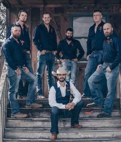 a group of men in cowboy hats standing on the steps of a building with their arms around each other