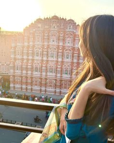 a woman standing on top of a balcony next to a building