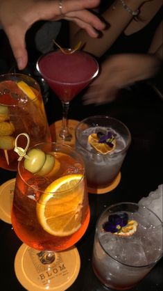 three glasses filled with different types of drinks on top of a black table next to each other