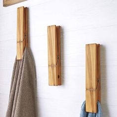 three wooden hooks are hanging on the wall next to two towels and one towel rack