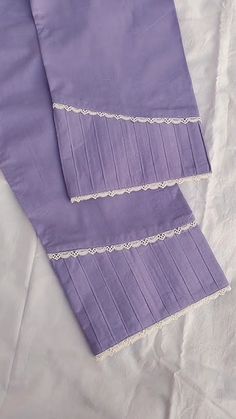 two purple napkins with white lace on them sitting on top of a tablecloth