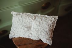 a white lace pillow sitting on top of a wooden table