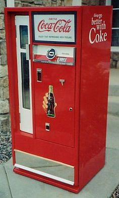 an old fashioned coca cola machine on the sidewalk