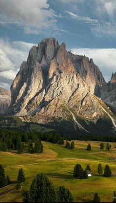 the mountains are covered in snow and clouds as they stand on top of green grass