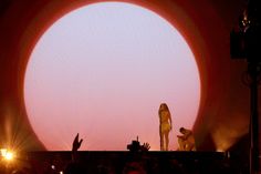 a person standing on top of a stage with their hands in the air and people watching