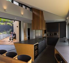 a man sitting on a bench in a kitchen next to an open floor plan with sliding glass doors