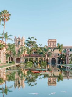 a pond in front of a large building with palm trees