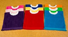 four different colored towels on the floor next to each other with white collars and bibs