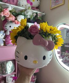 a hello kitty planter with sunflowers and daisies in front of a mirror