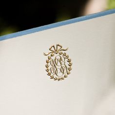 the monogrammed initials on the back of a white envelope are gold and blue