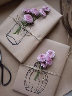 three packages tied up with twine and pink flowers