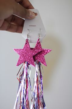 a pair of pink star shaped earrings with streamers hanging from it's sides