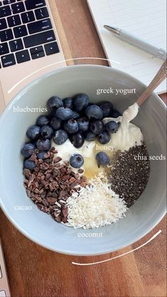 a bowl filled with blueberries, yogurt and other ingredients next to a laptop