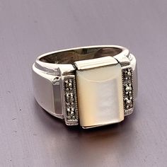 "Rectangle White Mother of Pearl and Marcasite Sterling Silver Vintage Ring ET504 Ring Size: 6.25: can be sized Metal Content: .925 Sterling Silver Face Height (North to South): 1/2\" (13mm) Face Width (East to West): 19/16\" (15m) Height of ring off of finger: 7mm Width of shank: tapers to 5 mm Gemstone: Mother of Pearl Size: 12mm by 9mm Weight: 7.8 Grams Stamps: .925 Condition: Excellent Vintage Condition Each piece is thoroughly examined and refinished as needed by our professional jewelers, Rectangular White Jewelry With Polished Finish, White Rectangular Jewelry With Polished Finish, White Rectangular Jewelry For Anniversary, Formal White Rectangular Ring, Classic White Rectangular Ring, Vintage White Rectangular Rings, White Rectangular Sterling Silver Ring, Formal Rectangular Ring Stamped 925, White Rectangular Gemstone Rings