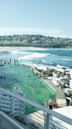 many people are swimming in the water at this beachside pool with white railings