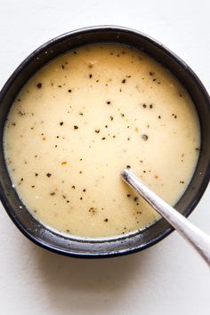 a black bowl filled with soup on top of a white table next to a spoon