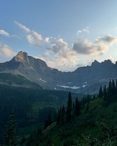 the mountains are covered in snow and trees as the sun is low on the horizon