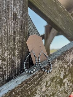 a pair of earrings hanging from a wooden fence with a tag attached to the ear