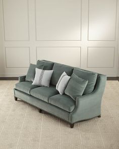 a green couch with pillows on it in front of a white paneled room wall