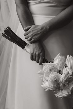 a bride and groom holding hands with their bouquets in black and white photo by wedding photographer