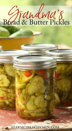 four jars filled with pickles sitting on top of a table