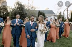 a bride and groom walking with their bridal party in front of the wedding venue