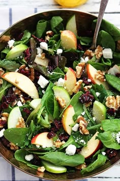 a salad with spinach, apples, walnuts and cranberries in a bowl