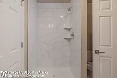 a bathroom with a walk in shower sitting next to a white door and toilet paper