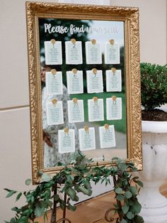 a wedding seating chart is displayed in front of a potted plant on a table