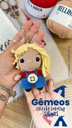 a hand holding a small crocheted doll in front of yarns and scissors