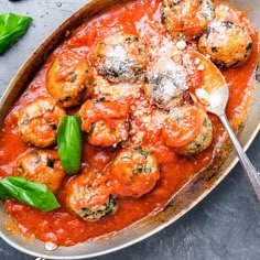 a pan filled with meatballs covered in tomato sauce and parmesan cheese on top