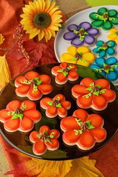 decorated pumpkin cookies on a plate with flowers and leaves in the background, along with pictures of them