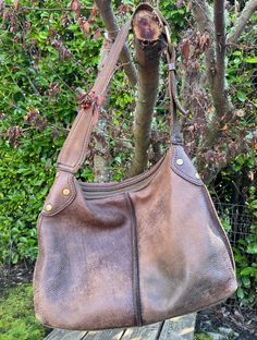 "Fantastic slouch hobo bag from vintage Lucky Brand, bag is brown leather with shoulder strap and zippered closure.  Antiqued brass ring and buckle, with brass grommets at the sides.  Dusty red fabric lining is intact, with zippered internal pocket.  Note that the lining was cut away from the shoulder strap, a great move in my opinion as the leather stays on the shoulder better.  Bag is in good vintage condition, very soft and well loved. Dimensions:   Height 12\" Width 16\" Depth 3\" Strap drop 12\"" Vintage Hobo Bag, Slouchy Leather Bag, Vintage Brown Bag, Vintage Soft Leather Hobo Bag, Vintage Brown Hobo Bag With Leather Backing, Vintage Brown Hobo Bag With Leather Handles, Vintage Brown Bohemian Leather Bag, Vintage Distressed Brown Shoulder Bag, Vintage Leather Bag