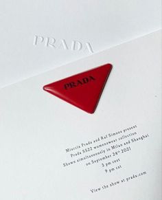 a close up of a piece of paper with a red triangle on it that says prada