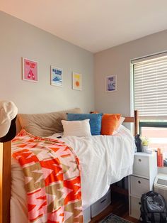 a bed sitting next to a window in a bedroom under a blanket and pillows on top of it