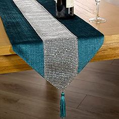 a table with a bottle of wine and two glasses on it, along with a blue runner