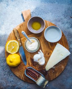 a wooden plate topped with different types of food on top of a table next to lemons