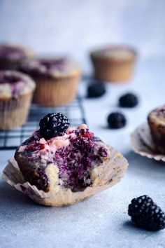 blueberry muffins with fresh blackberries on the top and one half eaten