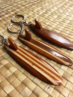 two wooden surfboard shaped key chains on a woven surface