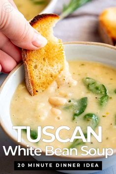 a hand dipping a piece of bread into a bowl of soup with the words tuscann white bean soup